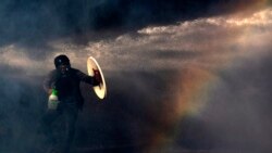 CHILE -– A demonstrator protects himself from the spray of a police water cannon with a makeshift shield during a protest against the government in Santiago, on November 26, 2019.