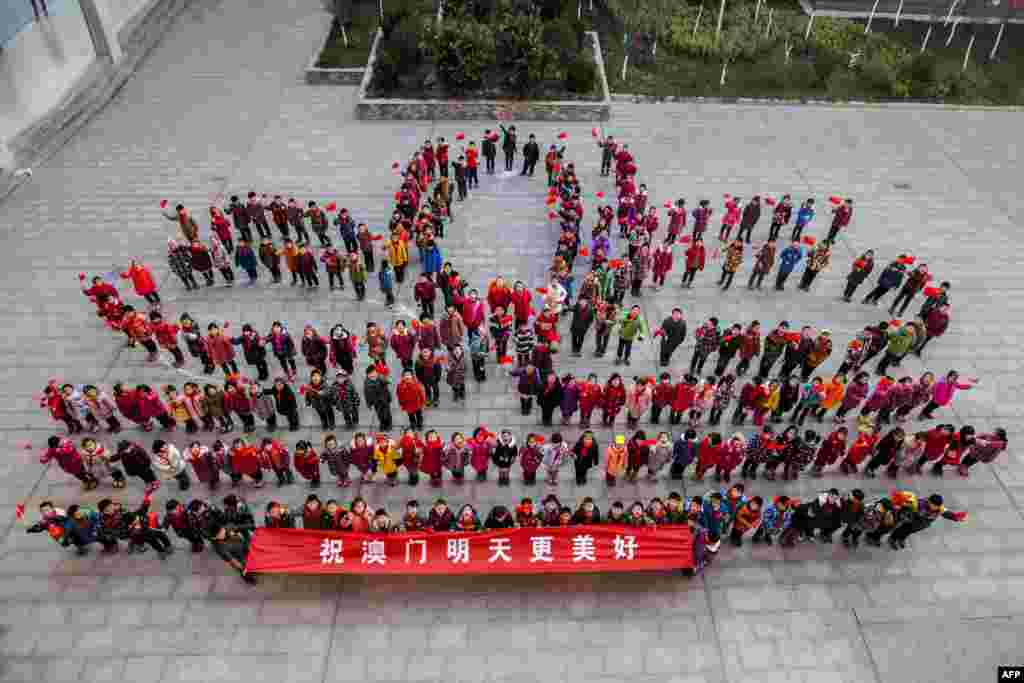 Para guru dan siswa berdiri dalam formasi bunga teratai untuk menandai ulang tahun ke-15 kembalinya daerah administratif khusus Macau ke China di sebuah SD di Lianyungang, Provinsi Jiangsu, China timur. Presiden Cina Xi Jinping mengunjungi Macau untuk perayaan ulang tahun itu. &nbsp;