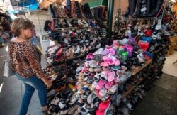 FILE - A woman shops for Chinese made shoes, Aug. 24, 2019, at a store in the Chinatown area of Los Angeles.