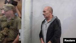 Volodymyr Tsemakh, suspected of involvement in the downing of the Malaysia Airlines Flight MH17 plane in 2014, stands inside a defendants' cage during a court hearing in Kyiv, Ukraine, Sept. 5, 2019. 