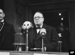 FILE - Winston Churchill approaches microphones to make a speech in January 1939.