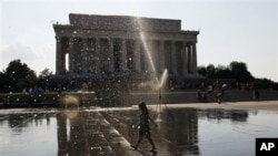 A young girls runs through a sprinkler set up for visitors to the Lincoln Memorial on the National Mall, where temperatures were in the 90s, Monday, July 2, 2012, in Washington. (AP Photo/Pablo Martinez Monsivais)