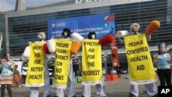 In Busan, members from Save The Children and World Vision stage a demonstration urging donor countries to fulfill their aid commitments.