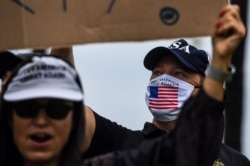 FILE - A supporter of President Donald Trump, right, wears a face mask as he participates in a "Freedom Rally" protest in support of lifting coronavirus restrictions in Florida, in South Beach in Miami, May 10, 2020.