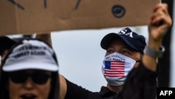 FILE - A supporter of President Donald Trump, right, wears a face mask as he participates in a "Freedom Rally" protest in support of lifting coronavirus restrictions in Florida, in South Beach in Miami, May 10, 2020.