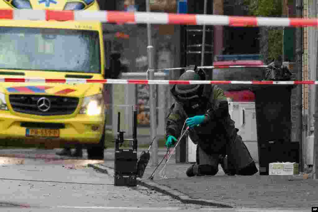 A member of the Explosive Ordnance Disposal team, EOD, examines a suspicious package after it was found on the doorstep of Kosher restaurant HaCarmel in Amsterdam, Netherlands.