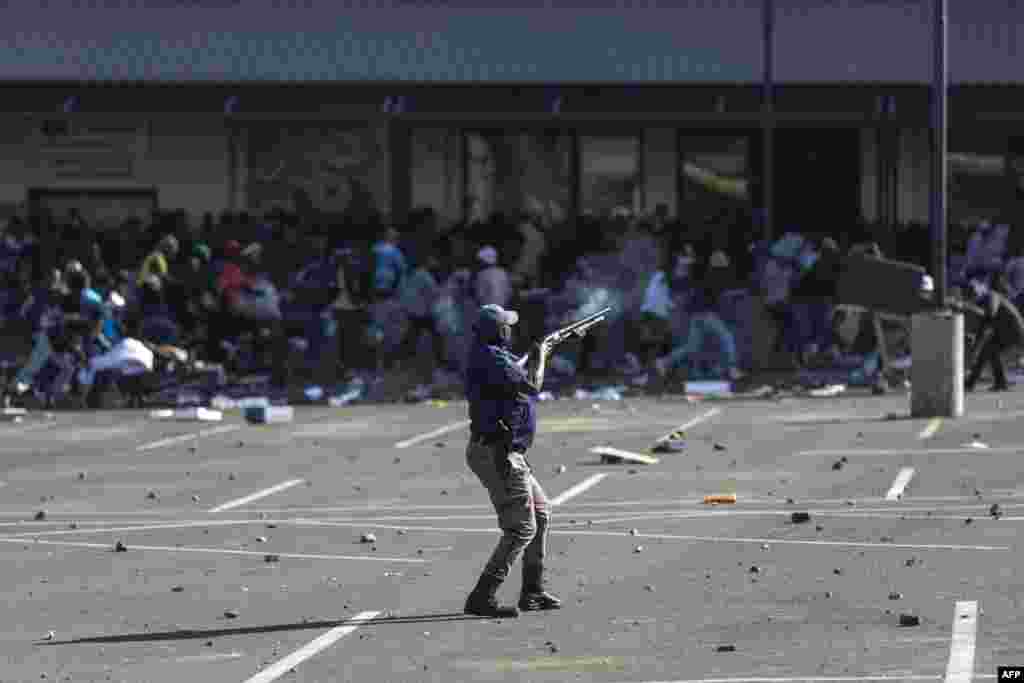 A member of the South African Police Services (SAPS) fires rubber bullets at rioters looting the Jabulani Mall in Soweto, southwest of Johannesburg.