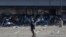 Un membre des services de police sud-africains (SAPS) tire des balles en caoutchouc sur des émeutiers pillant le centre commercial Jabulani à Soweto, au sud-ouest de Johannesburg, le 12 juillet 2021.