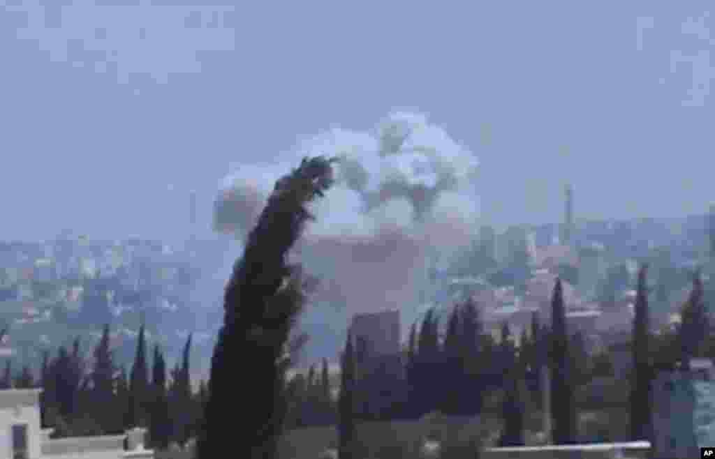 In this image taken from video obtained from the Shaam News Network, columns of smoke billow after heavy bombing, in the countryside outside of Aleppo, Syria, July 22, 2013. 