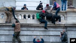 FILE - Insurrections loyal to President Donald Trump climb the west wall of the the U.S. Capitol, Jan. 6, 2021, in Washington.