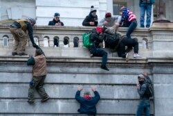 FILE - Insurrections loyal to President Donald Trump climb the west wall of the the U.S. Capitol, Jan. 6, 2021, in Washington.