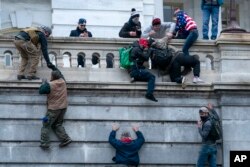 FILE - Insurrections loyal to President Donald Trump climb the west wall of the the U.S. Capitol, Jan. 6, 2021, in Washington.