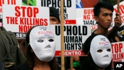 FILE - Masked protesters gather for a rally near the Presidential Palace to mark International Human Rights Day, Dec. 10, 2016, in Manila, Philippines. The protesters are calling on the government for an end to extrajudicial killings in the country.