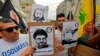 Protesters carry signs showing the faces of Lebanee Shiite movement Hezbollah leader Hassan Nasrallah and slain military commander Mustafa Badreddine as they march in an anti-US demonstration near US Embassy headquarters in Akwar, July 10, 2020. 