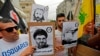 Protesters carry signs showing the faces of Lebanee Shiite movement Hezbollah leader Hassan Nasrallah and slain military commander Mustafa Badreddine as they march in an anti-US demonstration near US Embassy headquarters in Akwar, July 10, 2020. 