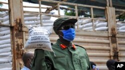 FILE - In this April 4, 2020, photo, a member of the Uganda People's Defence Force (UPDF) helps to distribute food to people affected by the lockdown measures aimed at curbing the spread of the new coronavirus in Kampala, Uganda.