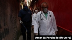 Medical personnel walk through the city's biggest slum Paraisopolis after residents have hired a round-the-clock private medical service, in Sao Paulo, Brazil March 30, 2020. (REUTERS/Amanda Perobelli )