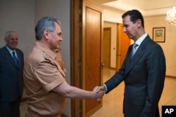 Syrian President Bashar al-Assad shakes hands with Russian Defense Minister Sergei Shoigu in Damascus, June 18, 2016.