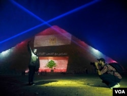 The usual light show at the Giza pyramid complex in Egypt was suspended on Sunday, replaced by lights depicting Lebanese, French and Russian flags and messages of solidarity, Nov. 15, 2015. (VOA/Hamada Elrasam/VOA)