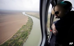 In this Feb. 24, 2015, aerial file photo, a U.S. Customs and Border Protection Air and Marine agent looks out along the Rio Grande on the Texas-Mexico border in Rio Grande City, Texas.