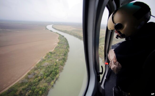 Un agente de la fuerza de Aduanas y Protección Fronteriza monitorea la frontera desde un helicóptero a lo largo del Rio Grande, en la frontera con México.