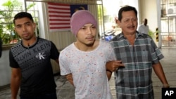Wee Meng Chee (tengah), rapper Malaysia yang dikenal dengan nama panggung Namewee, dikawal polisi berpakaian preman di pengadilan di Penang (22/8). (AP/Gary Chuah)