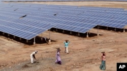 FILE - Indian laborers work near solar panels at the Gujarat Solar Park at Charanka in Patan district, about 250 kilometers (155 miles) from Ahmadabad, India.