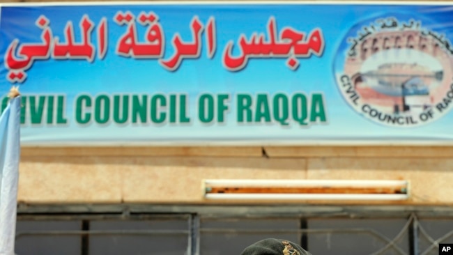 FILE - A sign for the Civil Council of Raqqa is seen on a building in Ain Issa on the northern outskirts of the former self-proclaimed Islamic State capital in Syria, July 23, 2017.