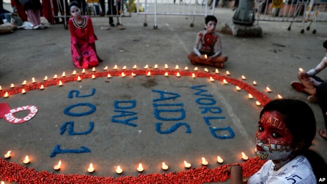 People light candles in the formation of a red ribbon, the universal symbol of awareness and support for those living with HIV, on World AIDS Day in Kolkata, India, Dec. 1, 2021.