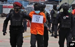 Polisi mengawal seorang terduga teroris setibanya di Bandara Internasional Soekarno-Hatta, Kamis, 18 Maret 2021. (Foto: AP)