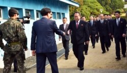 FILE - The head of the North Korean delegation Ri Son Gwon, center, is greeted by an unidentified South Korean official as Ri crosses to the South side for the meeting with South Korea at Panmunjom in the Demilitarized Zone, Oct. 15, 2018.