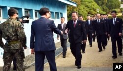 FILE - The head of the North Korean delegation Ri Son Gwon, center, is greeted by an unidentified South Korean official as Ri crosses to the South side for the meeting with South Korea at Panmunjom in the Demilitarized Zone, Oct. 15, 2018.