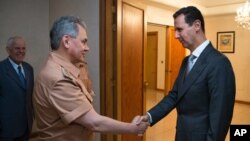 Presiden Suriah Bashar al-Assad berjabat tangan dengan Menteri Pertahanan Sergei Shoigu di Damaskus (18/6). 