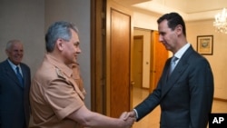 Syrian President Bashar al-Assad shakes hands with Russian Defense Minister Sergei Shoigu in Damascus, June 18, 2016. 