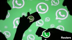 Hombres posan con teléfonos inteligentes frente al logotipo de Whatsapp que se muestra en esta ilustración el 14 de septiembre de 2017. REUTERS / Dado Ruvic