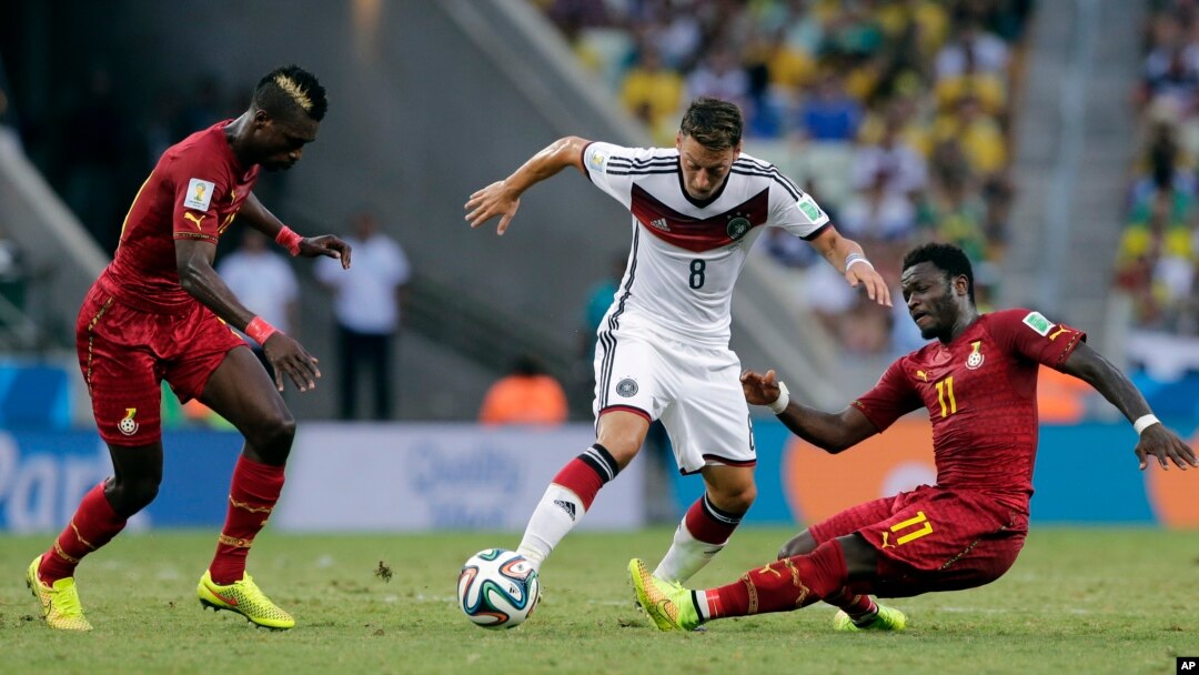 Germany's Mesut Ozil, center, is challenged by Ghana's Sulley Muntari, right, during the group G World Cup soccer match at the Arena Castelao in Fortaleza, Brazil, June 21, 2014. 