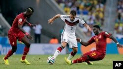 Germany's Mesut Ozil, center, is challenged by Ghana's Sulley Muntari, right, during the group G World Cup soccer match at the Arena Castelao in Fortaleza, Brazil, June 21, 2014. 