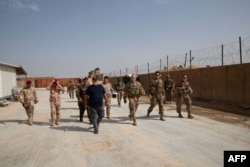 A handout picture released by the US Central Command on March 17, 2020, shows Qaim base commander US Major Luc Taylor, second from right, giving a tour of the base to the Iraqi Army aviation battalion.