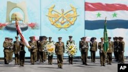 In this photo released by the Syrian official news agency SANA, Syrian honor guard soldiers carry the coffins of Syrian army soldiers who were killed in recent violence in the country, during their funeral procession at the military hospital, in Damascus,