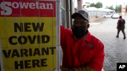 A petrol attendant stands next to a newspaper headline in Pretoria, South Africa, Nov. 27, 2021. 