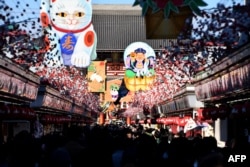 Visitors walk underneath New Year's Day decorations celebrating next year's "Year of the Dog" from the Chinese zodiac at the Nakamise shopping alley, the front approach to Sensoji Temple, in Tokyo, 2017.