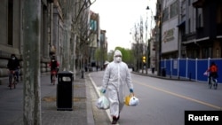 A man in a hazmat suit walks in Wuhan, Hubei province, the epicenter of China's coronavirus disease (COVID-19) outbreak, March 28, 2020.