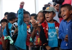 FILE - Children cheer for community policemen who delivered toys as part of the Children's Day festivities, in Alcozacan, Guerrero state, Mexico, Friday, April 30, 2021. Community leaders have worked to keep children away from drug gangs.