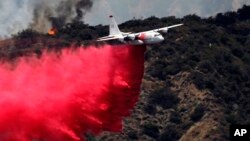 Pesawat pemadam kebakaran menjatuhkan zat pemadam untuk mengendalikan kebakaran hutan dekat Bradbury, California (22/6). (AP/Nick Ut)