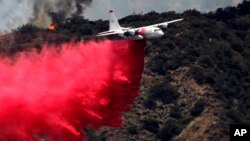 Sebuah pesawat pemadam kebakaran berusaha memadamkan kebakaran kawasan hutan di Bradbury, California (22/6). 