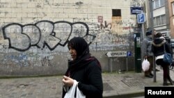 A woman passes close to the house where Salah Abdeslam, the most-wanted fugitive from November's Paris attacks, was arrested on March 18 after a shootout with polic in the Brussels district of Molenbeek, March 19, 2016.