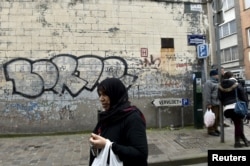 A woman passes close to the house where Salah Abdeslam, the most-wanted fugitive from November's Paris attacks, was arrested on March 18 after a shootout with polic in the Brussels district of Molenbeek, March 19, 2016.