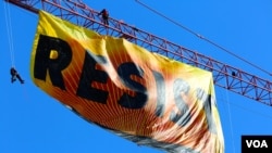 Manifestantes de Greenpeace colocan una bandera con el rótulo "RESIST," a solo unas cuadras de la Casa Blanca. (B. Allen / VOA)