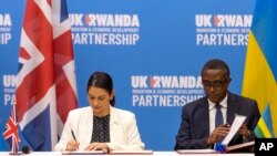 Britain's Home Secretary Priti Patel (L) and Rwanda's Minister of Foreign Affairs Vincent Biruta (R) sign what the migration deal in Kigali, Rwanda Thursday, April 14, 2022.