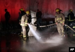 Afghan firefighters wash the site of a twin bombing in Kabul, Afghanistan, Jan. 10, 2017.